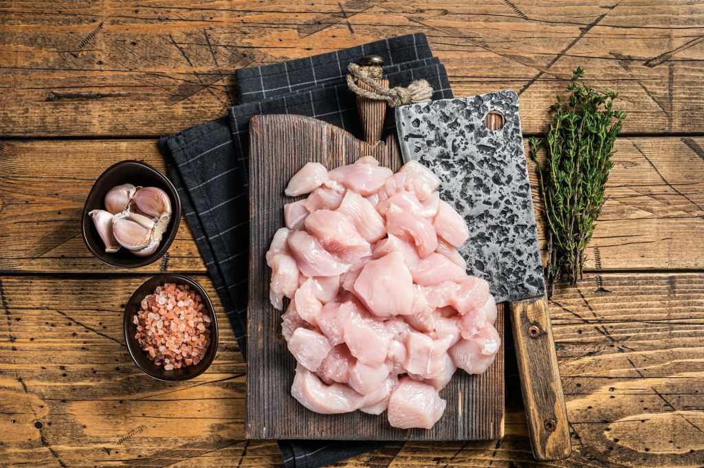 Raw chicken fillet cut into cubes, Uncooked sliced poultry meat, on wooden board.