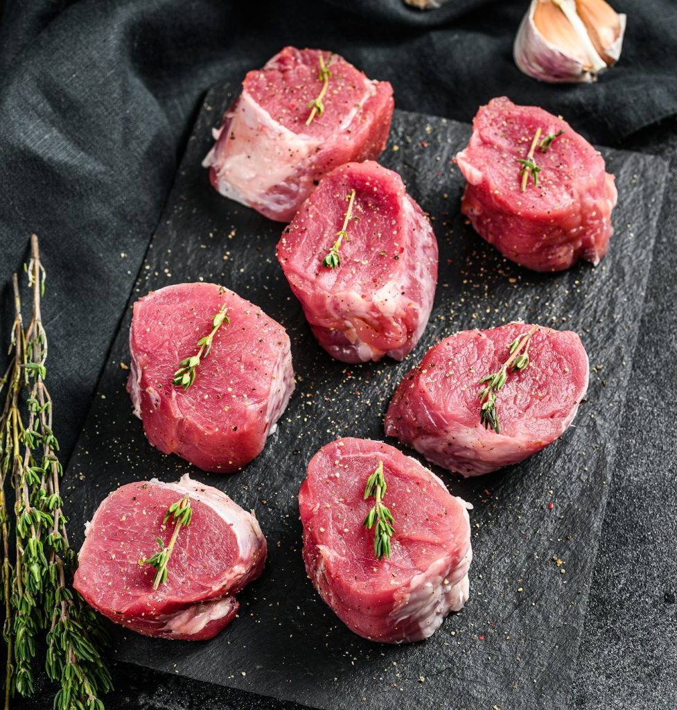 Raw pork medallion steaks. Pork meat fillet. black background. Top view